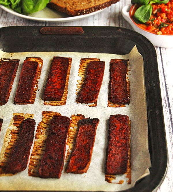 baked tofu bacon strips on baking tray lined with parchment paper.