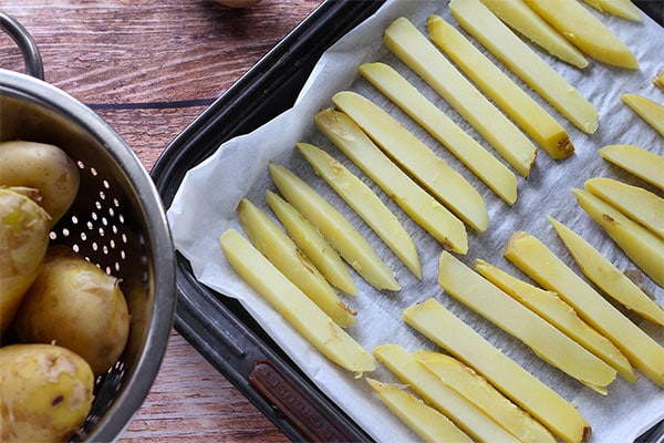 potatoes are sliced, cut into strips and placed on a baking try with parchment paper.