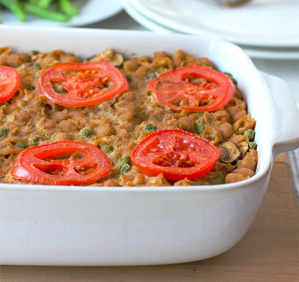 white oblong baking dish with tuna casserole with sliced tomatoes on top.