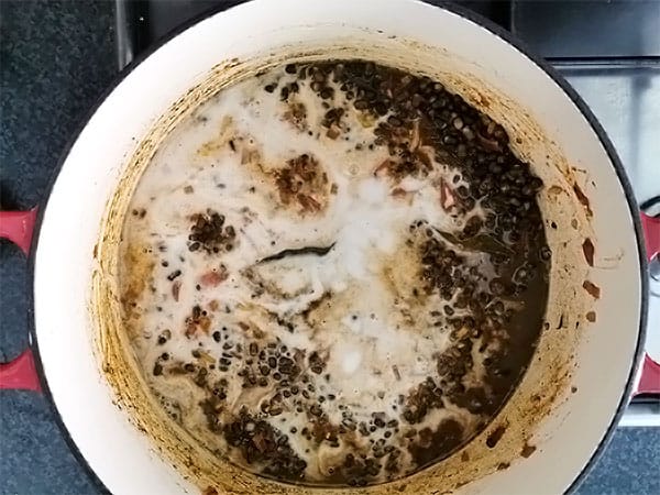 coconut milk added to black lentil dal on stove top.