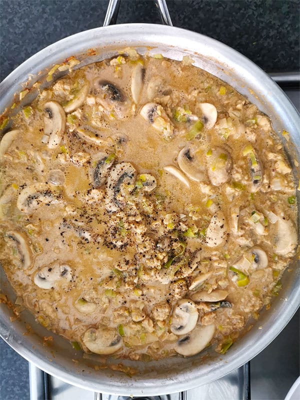 Tempeh mushroom stroganoff simmering in stainless steel pan.