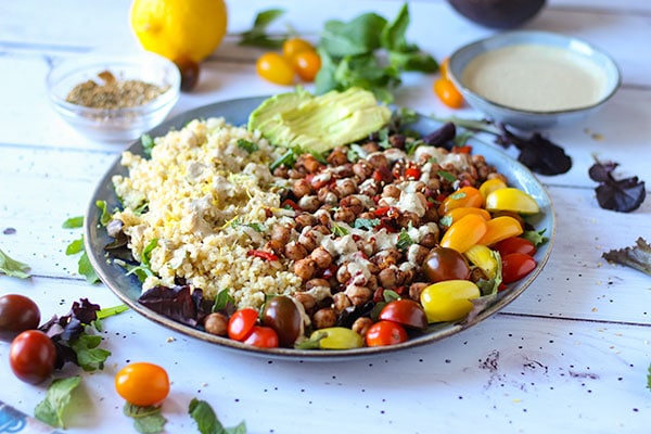 Middle Eastern chickpea salad with lettuce greens, chickpeas, bulgur, cherry tomatoes, dressing and sliced avocado.