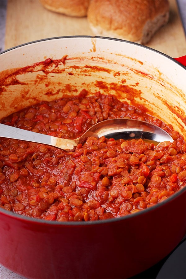 Filling for vegan lentil sloppy joes in red pot with spoon.