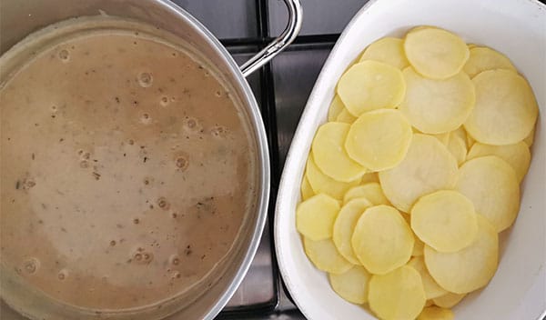 pan with vegan scalloped potato sauce and white dish with sliced potatoes.