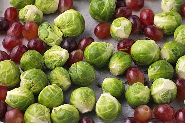 tray with Brussels sprouts and grapes on parchment paper