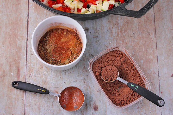 Overhead shot of mixed chili spices and container of cocoa powder