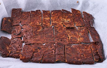 plant-based bacon cut into strips and flipped on parchment paper