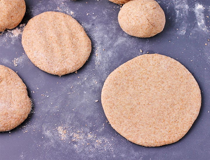 Unbaked whole wheat pita bread dough is separated and formed into discs