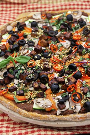 sweet potato crust pizza with black olives, smoked tofu, red peppers on red checkered cloth