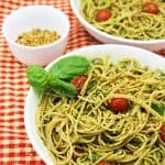 pesto & hemp parmesan spaghetti in white bowl on red checkered cloth with another bowl in background