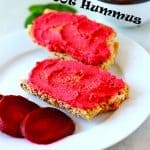 pink beetroot hummus on bread slices on white plate with sliced red beets and recipe text in black