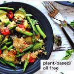 zucchini green bean salad with Tahini dressing on black plate with fresh mint and recipe title in black text and logo.