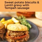 Sweet potato biscuits are loaded with Tempeh sausage patties and smothered in lentil gravy on a black plate text overlay in orange with recipe title.