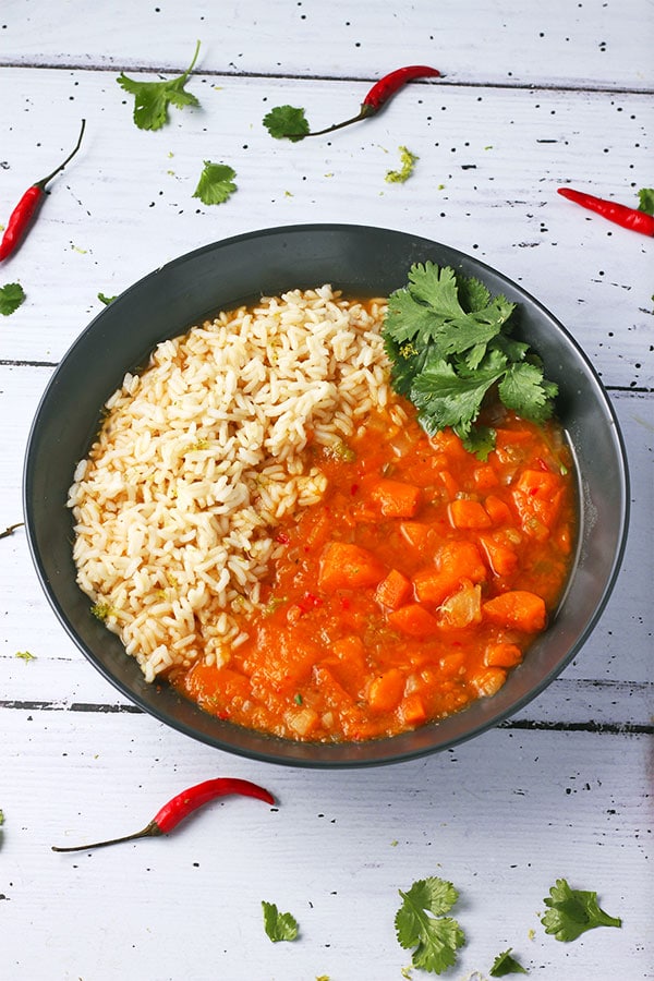 Thai sweet potato curry with rice in black bowl.
