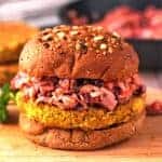 Baked chickpea burgers with spicy coleslaw and bun on wooden board.