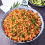Blue bowl filled with cooked bulgur with vegetables and tomatoes