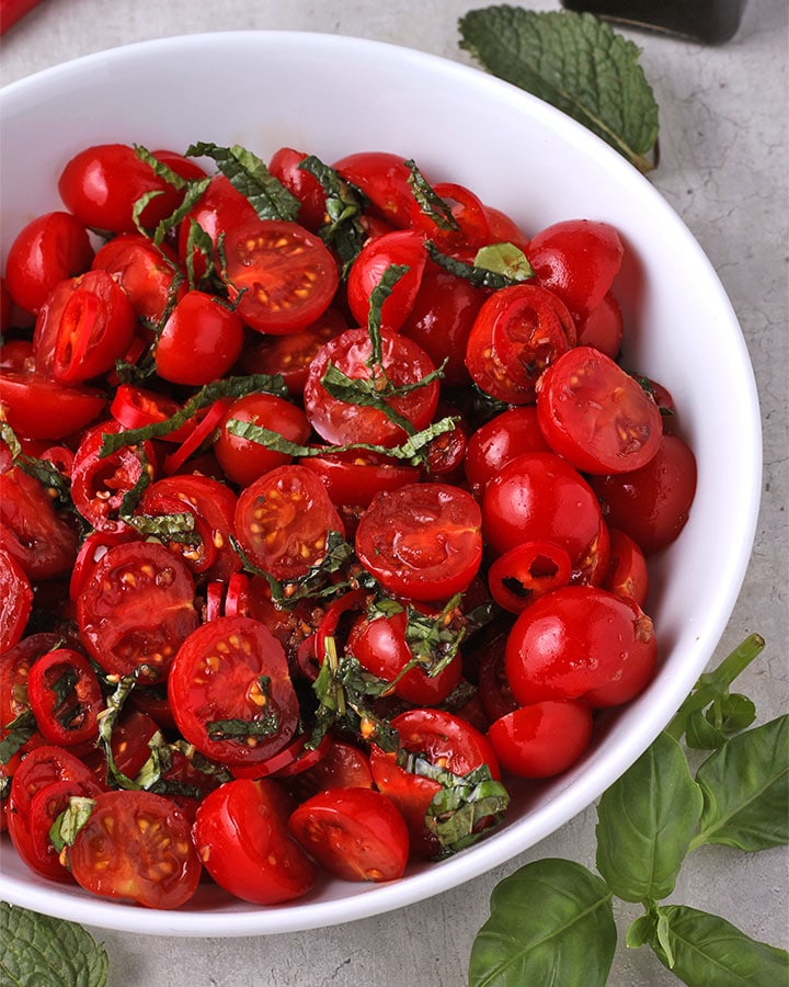 Thai tomato salad with sliced cherry tomatoes, fresh basil and mint in white bowl