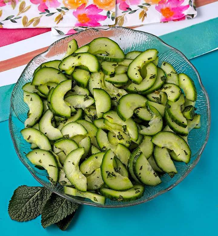 sliced cucumber with chopped mint in glass dish