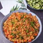 Blue bowl filled with cooked bulgur with vegetables and tomatoes and text overlay with recipe title.