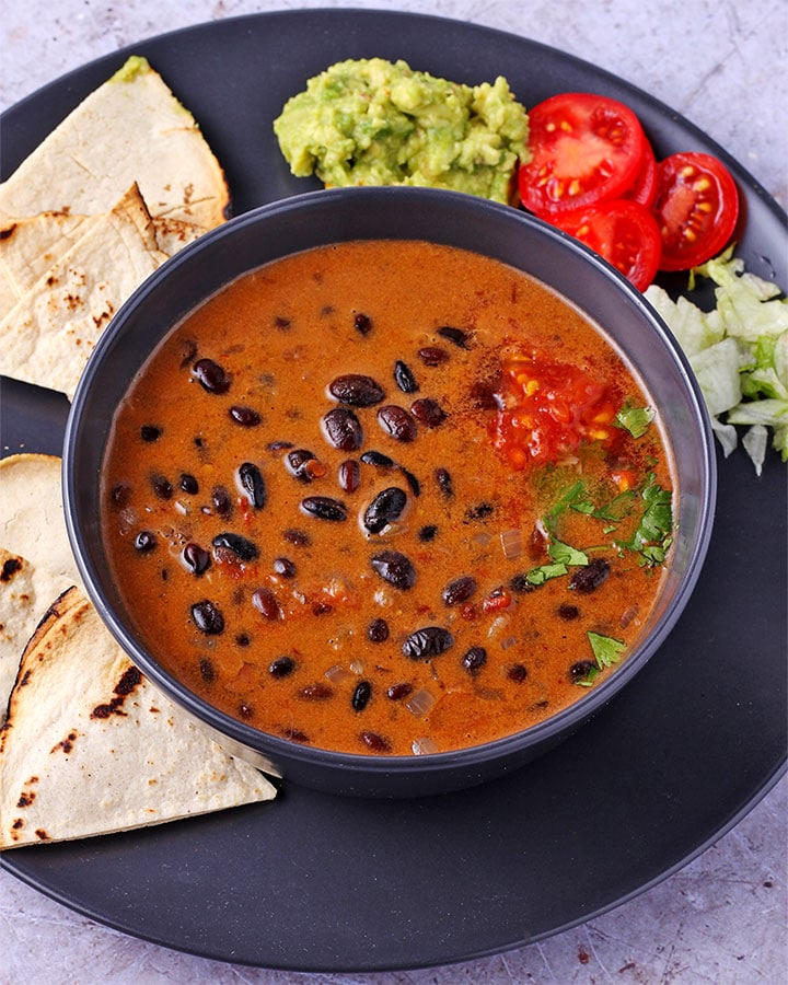 saucy chipotle black beans in coconut-chipotle pepper sauce in black bowl.