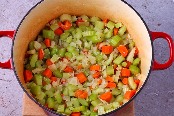 Diced onions, carrots and celery is added to soup pot.