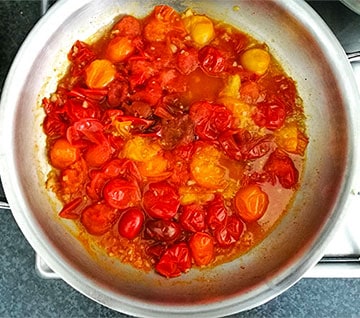 Fresh cherry tomatoes are poached in vegetable broth in skillet