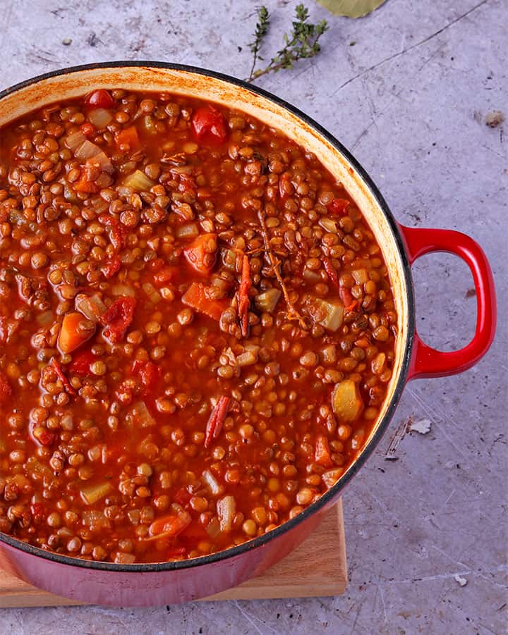 Overhead shot of pot filled with lentil tomato soup with diced celery, onions and carrots