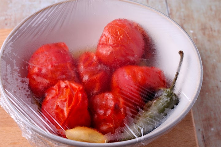 Roasted tomatoes, jalapeno and garlic placed in bowl and covered with plastic wrap