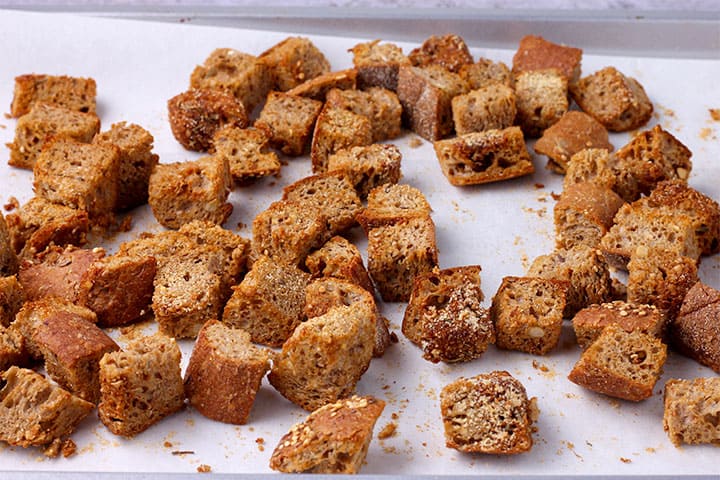 bread cubes are toasted on baking tray with parchment paper