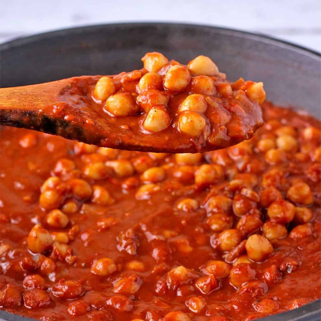 chickpea curry masala (tikki masala) with tomato sauce in black pan with wooden spoon