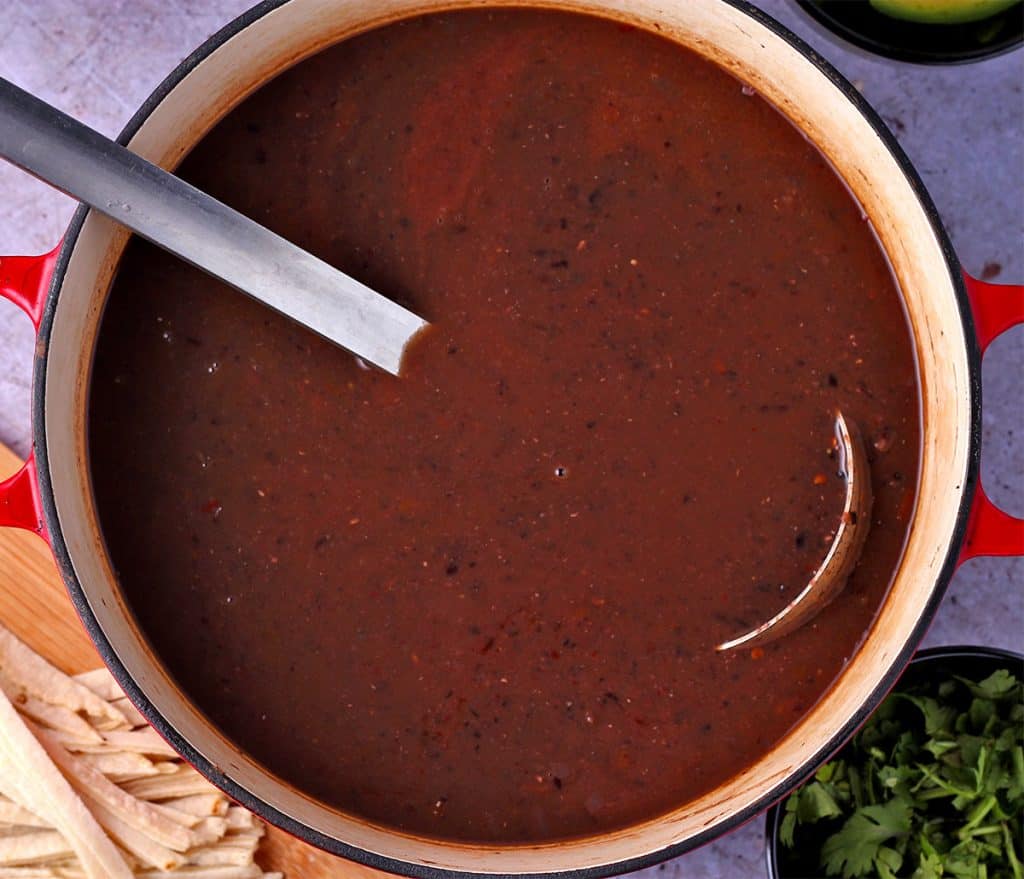 creamy pureed black bean soup in red soup pot