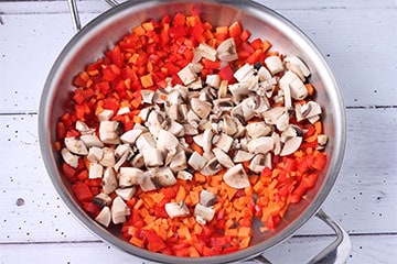 Raw diced carrots, mushrooms and red pepper in steel pan