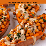 Baked sweet potato halves with chickpeas, dressing and chopped mint on top.