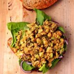 chickpea salad on top of a slice of bread, lettuce leaves and red onion slices