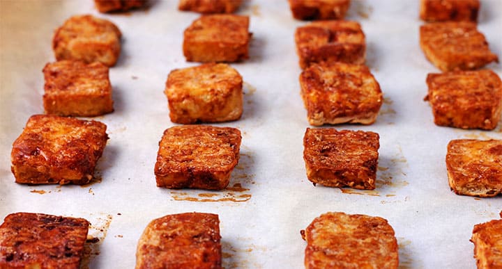 browned and baked tofu cubes on parchment paper baking tray