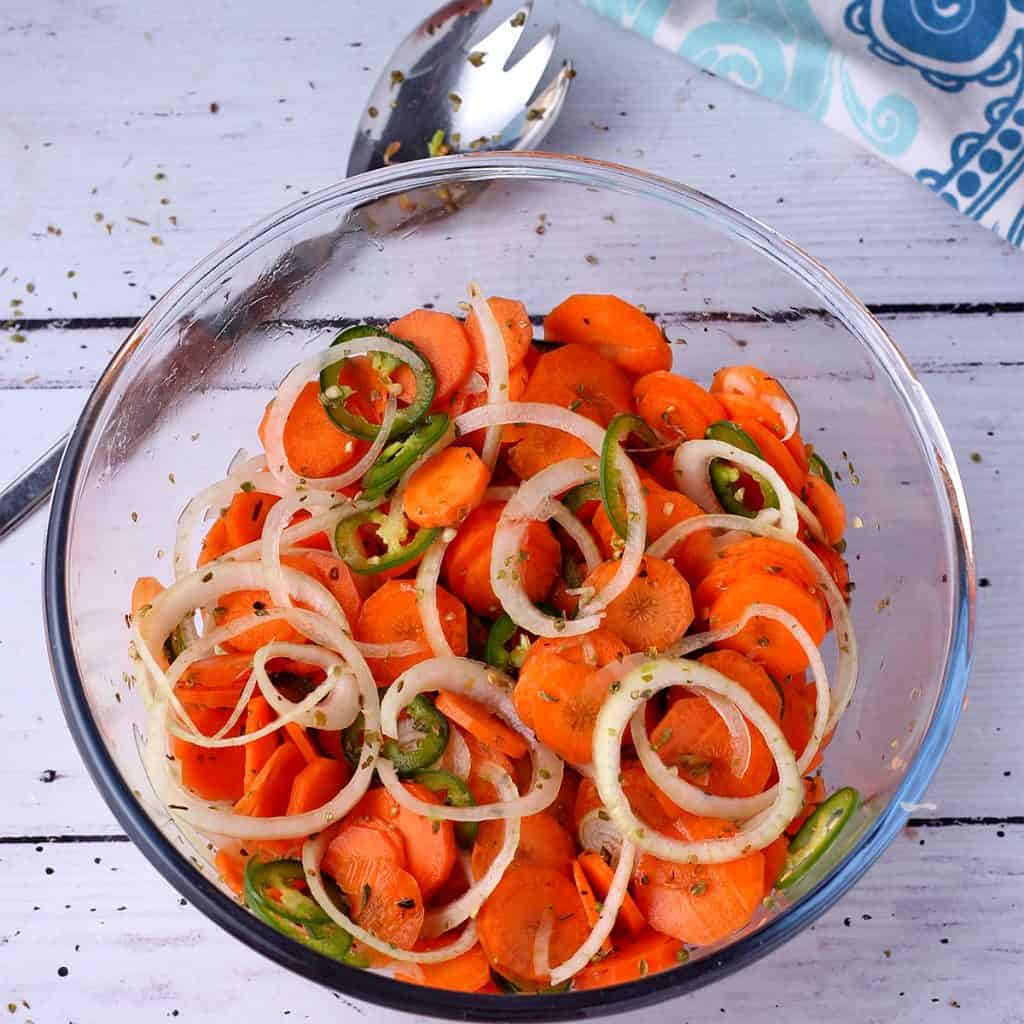 pickled carrots, onions and jalapenos with oregano in glass bowl.