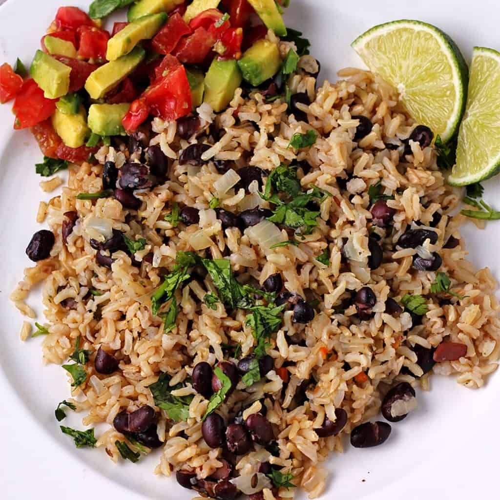 overhead shot of cooked rice and black beans with chopped cilantro on white plate