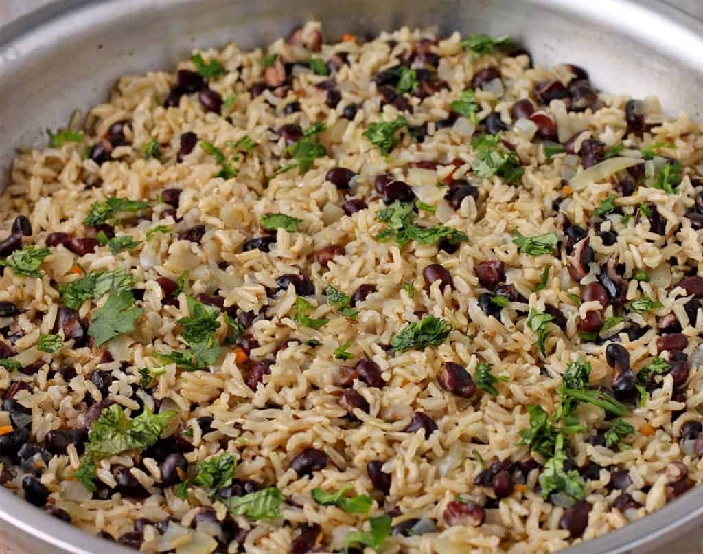 close up of cooked rice and beans with onions and chopped cilantro in skillet