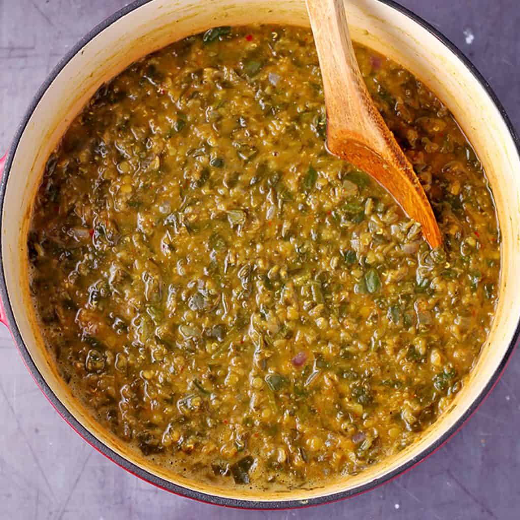spinach curry in pot with wooden spoon