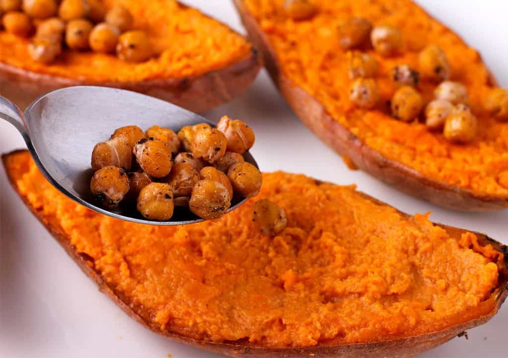 Baked chickpeas are spooned onto a baked sweet potato half.