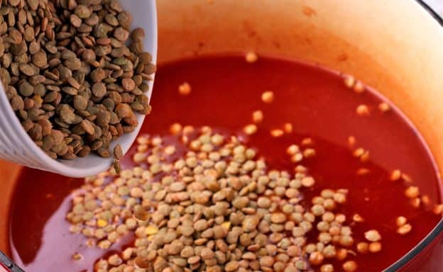 Dry green lentils are added to Diavolo sauce in red pot