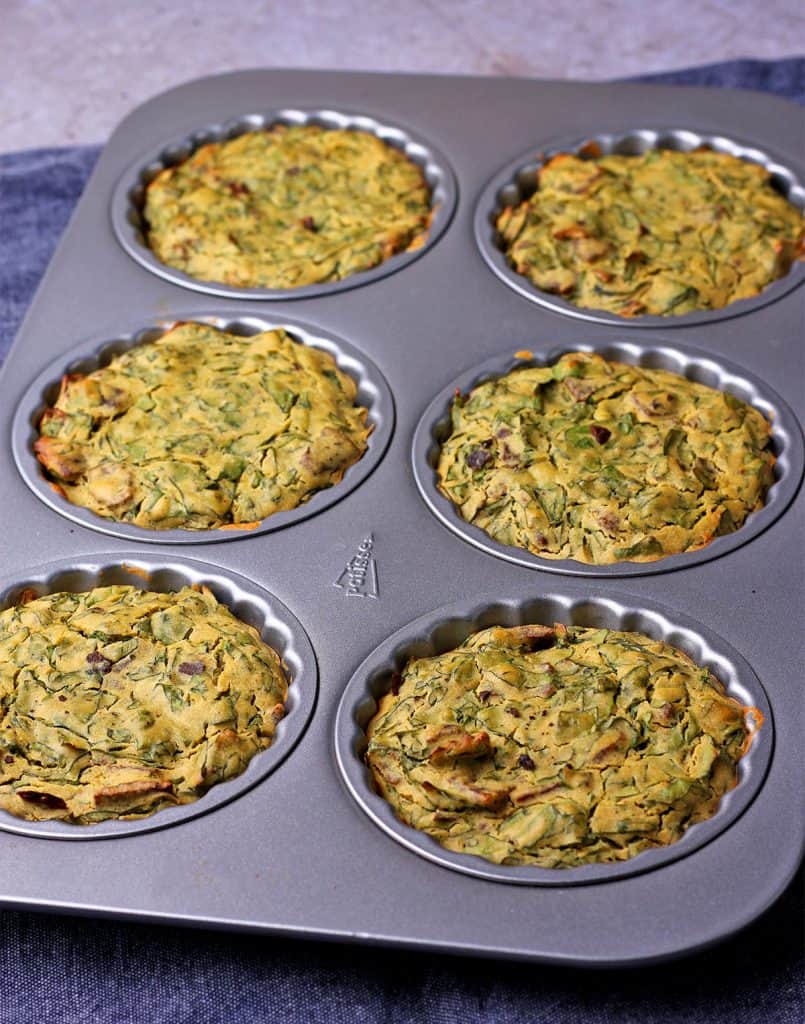 vegan mini quiches with spinach and bacon is baked in a muffin tin.