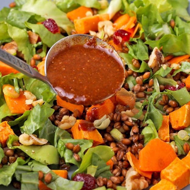 soy ginger dressing is added to salad of roasted sweet potatoes, endive, cranberries, walnuts, carrots, and wheat berries