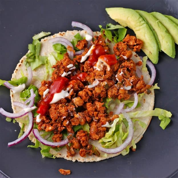 Taco made with tempeh crumbles, lettuce, onions, plant-based sour cream, and salsa
