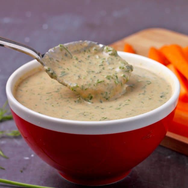 tahini ranch dressing in red bowl with silver spoon