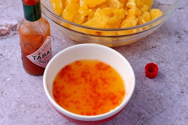 a small bowl with orange juice and Tabasco sauce.