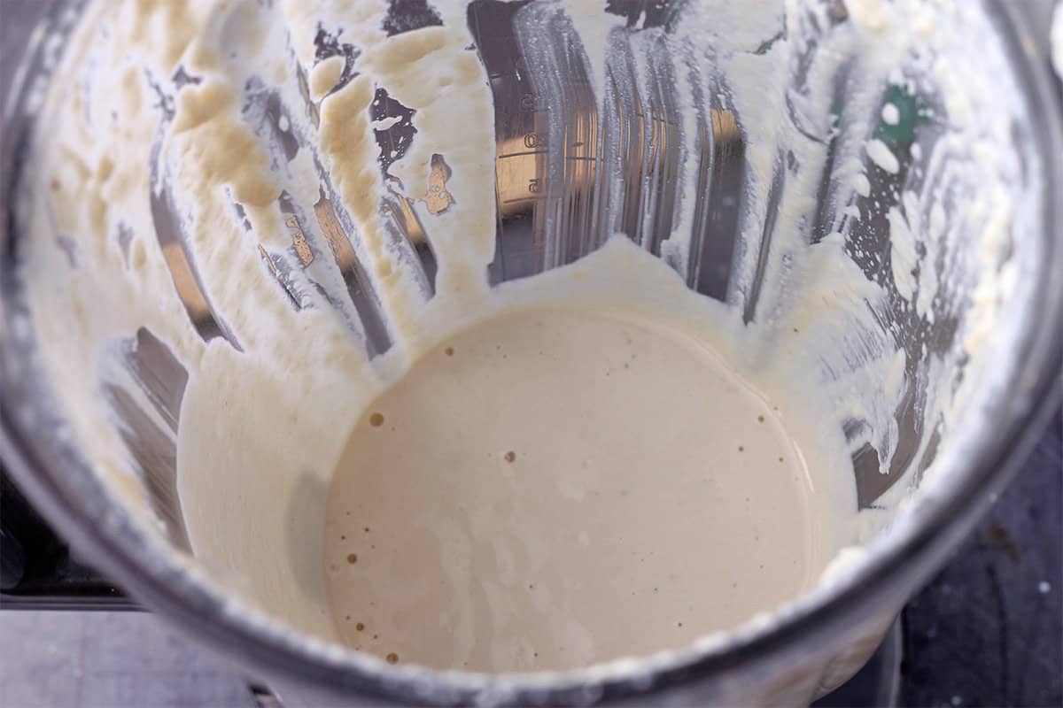 A blender is filler with plant-based sour cream.