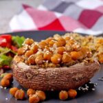 Chickpeas whole and mashed make vegan stuffed Portobello mushrooms that are topped with sesame seeds.