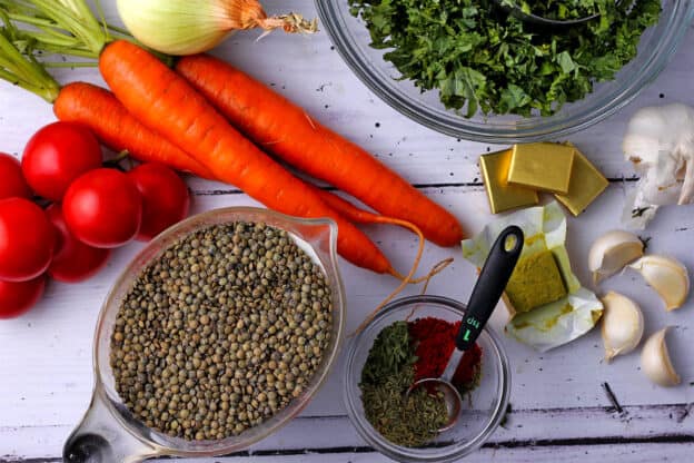 Ingredients for vegan French Lentil soup include lentils, tarragon, thyme, paprika, garlic, onions, carrots, tomatoes, vegetable broth, and kale.