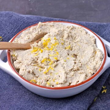 A white dish of tofu ricotta with lemon zest on top.